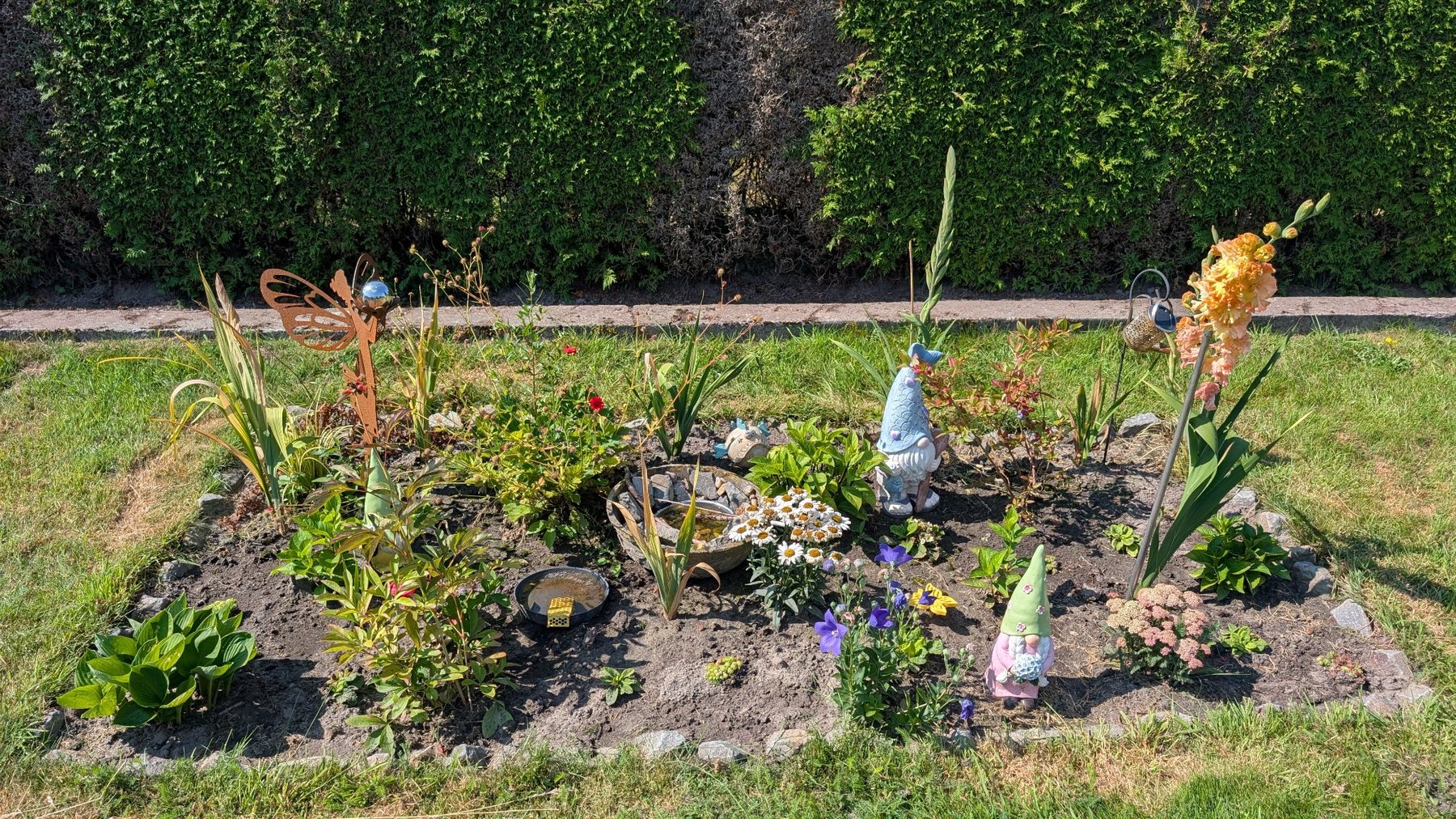 Bepflanzte Staudeninsel mit Gartendekoration