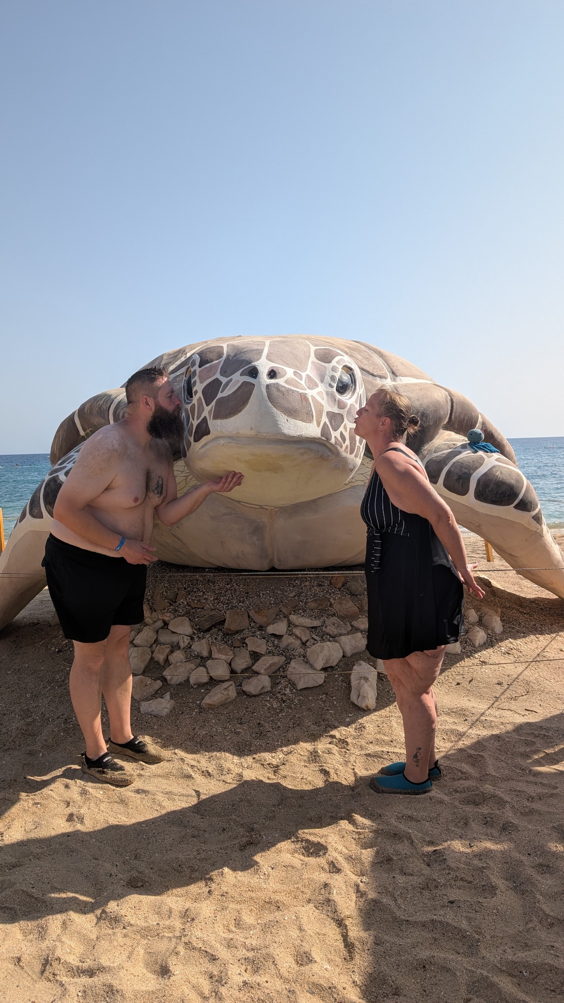 Sanni und Thomas vor einer großen Schildkrötenfigur am Strand