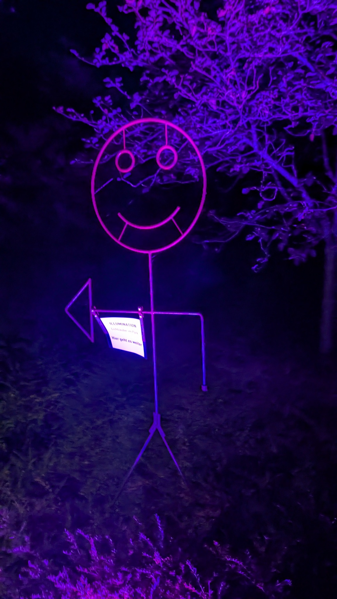 Violett beleuchtete lächelnde Wegweiserfigur